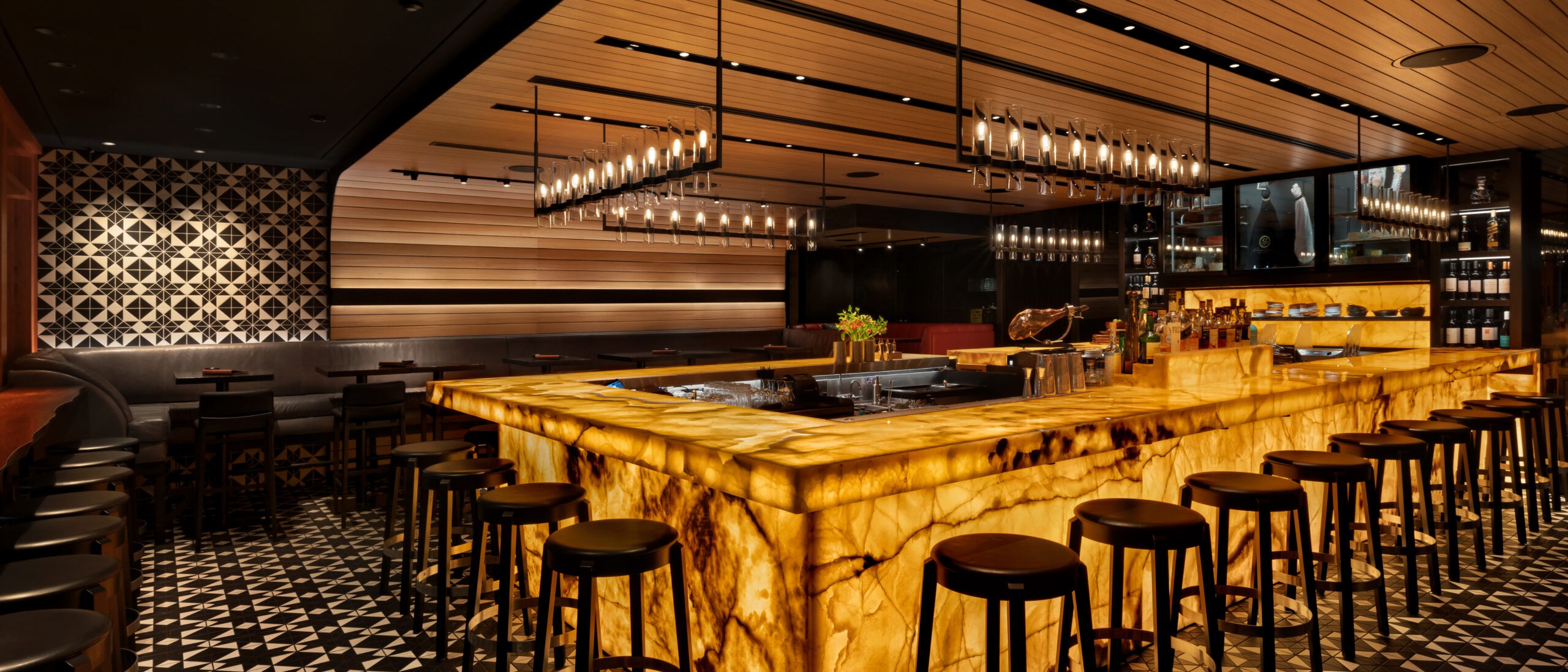 Inside Bar Oso: the U-shaped backlit onyx bar glowing under candle-style pendants